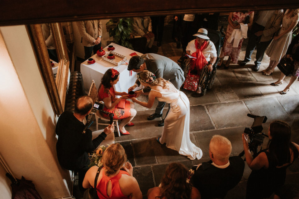 chinese wedding tea ceremony - a couple offering tea to a seated woman - there are people watching including women in wheelchair