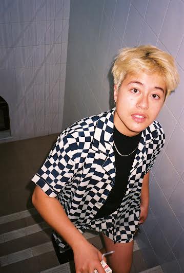 East Asian with blondish short hair wearing a checkered black and white sirt and shorts